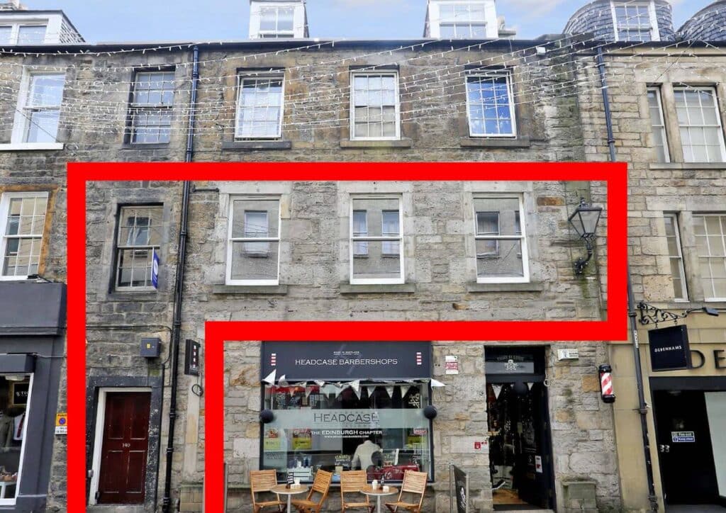 Stone building with Headcase barbershop and outdoor seating, surrounded by festive string lights.