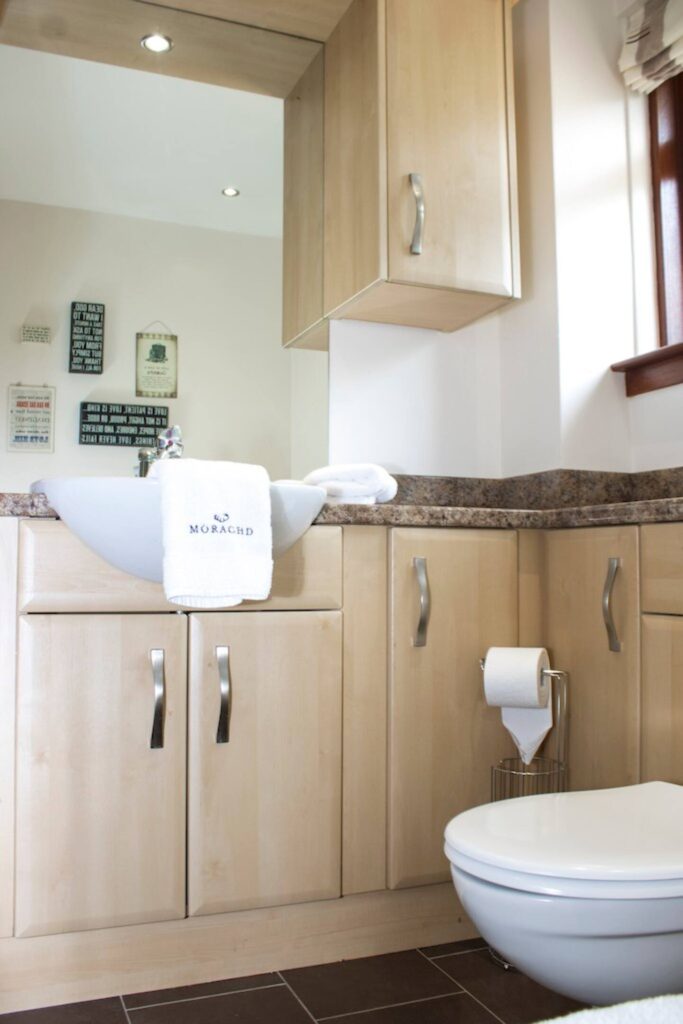 Modern bathroom with wooden cabinets, sink, towel, and toilet. Cozy and clean interior design.