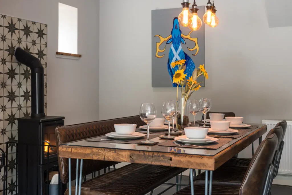 Cozy dining area with rustic table, sunflowers, and modern decor, under warm lighting beside a stylish stove.