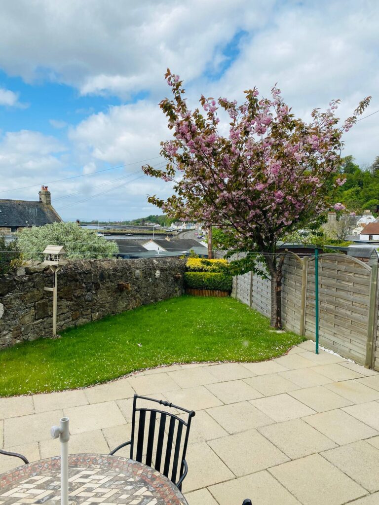 Charming garden patio with flowering tree and scenic views, perfect for relaxing outdoors.