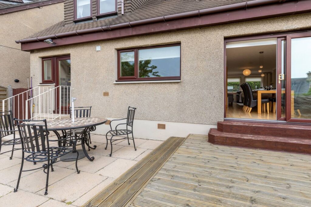 Outdoor patio with metal chairs and table, leading to home interior through sliding glass doors.