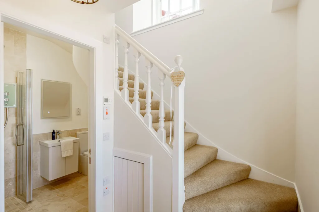 Cozy home interior with carpeted stairs and modern bathroom featuring beige tiles and white fixtures.