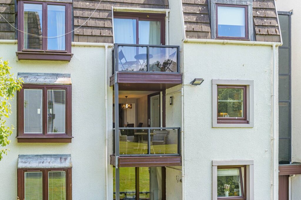 Modern apartment exterior with glass balcony and large windows.