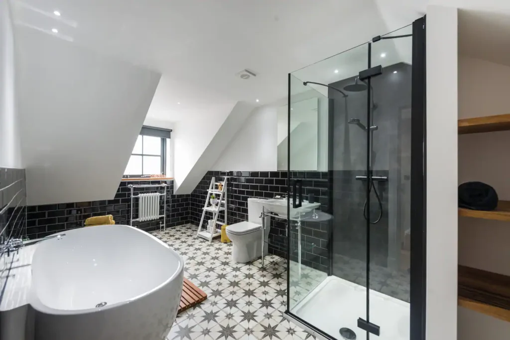 Modern bathroom with a freestanding tub, glass shower, and patterned tile floor in a loft-style space.