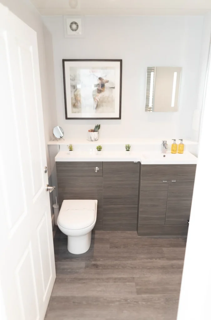 Modern bathroom with sleek cabinetry, toilet, minimal decor, and a wall-mounted artwork, reflecting contemporary design.