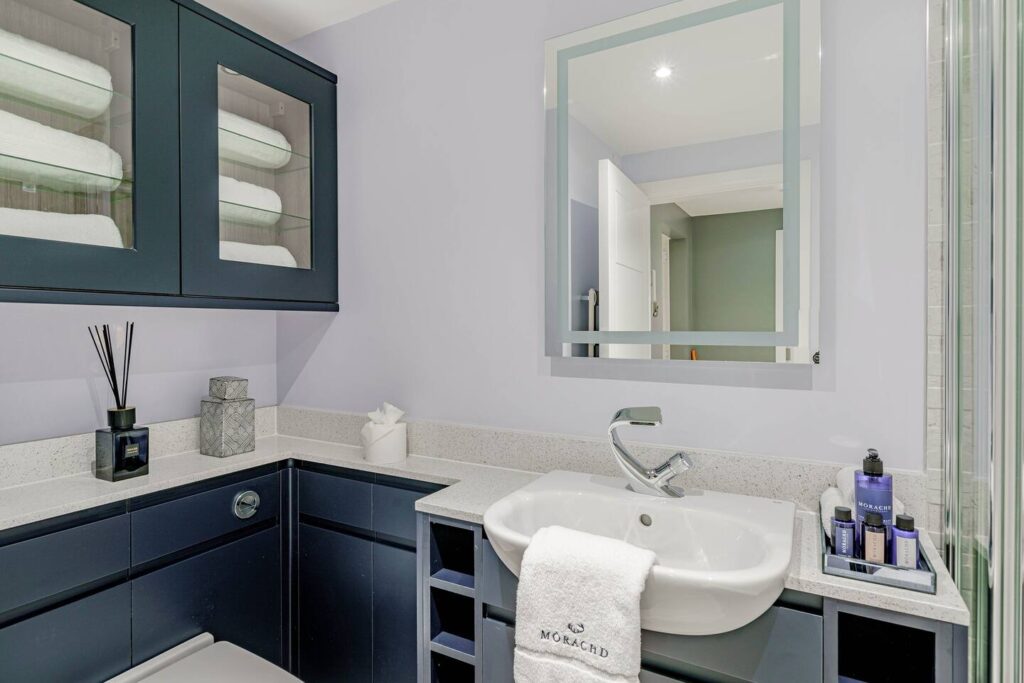 Modern bathroom with white sink, sleek dark cabinets, towels, and toiletries, reflecting contemporary design and elegance.