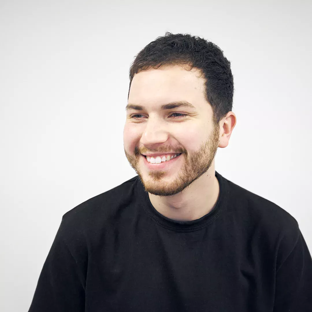 Smiling man with a beard wearing a black shirt against a white background.